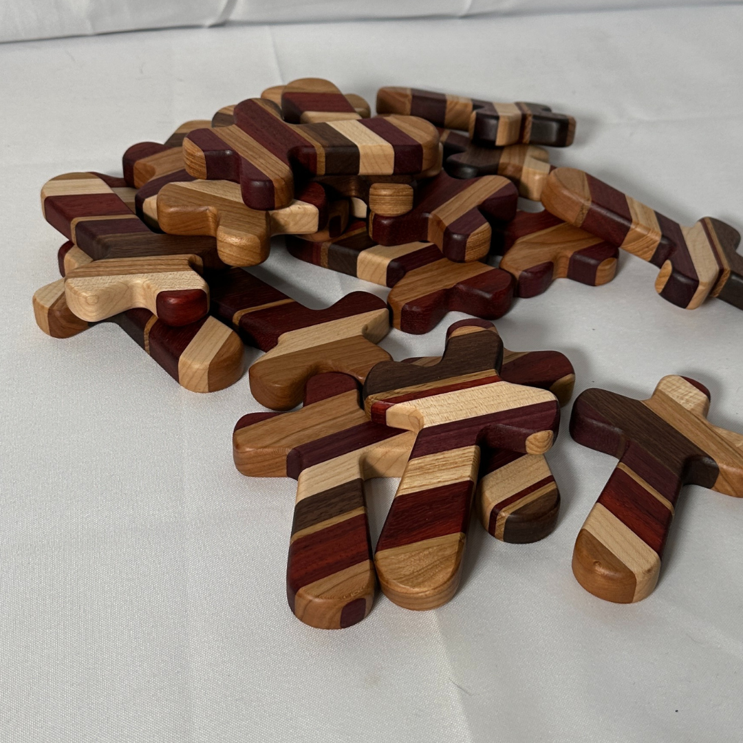 Experience the perfect blend of faith, craftsmanship, and personalization with our Handcrafted Wooden Prayer Cross. Measuring approximately 5" x 3-1/4", this hand-sized cross is thoughtfully designed for prayer, meditation, and comfort. Crafted from premium hardwoods, including purple heart, paduak, hard maple, walnut, white oak, and cherry, each cross showcases a stunning array of natural tones and textures.