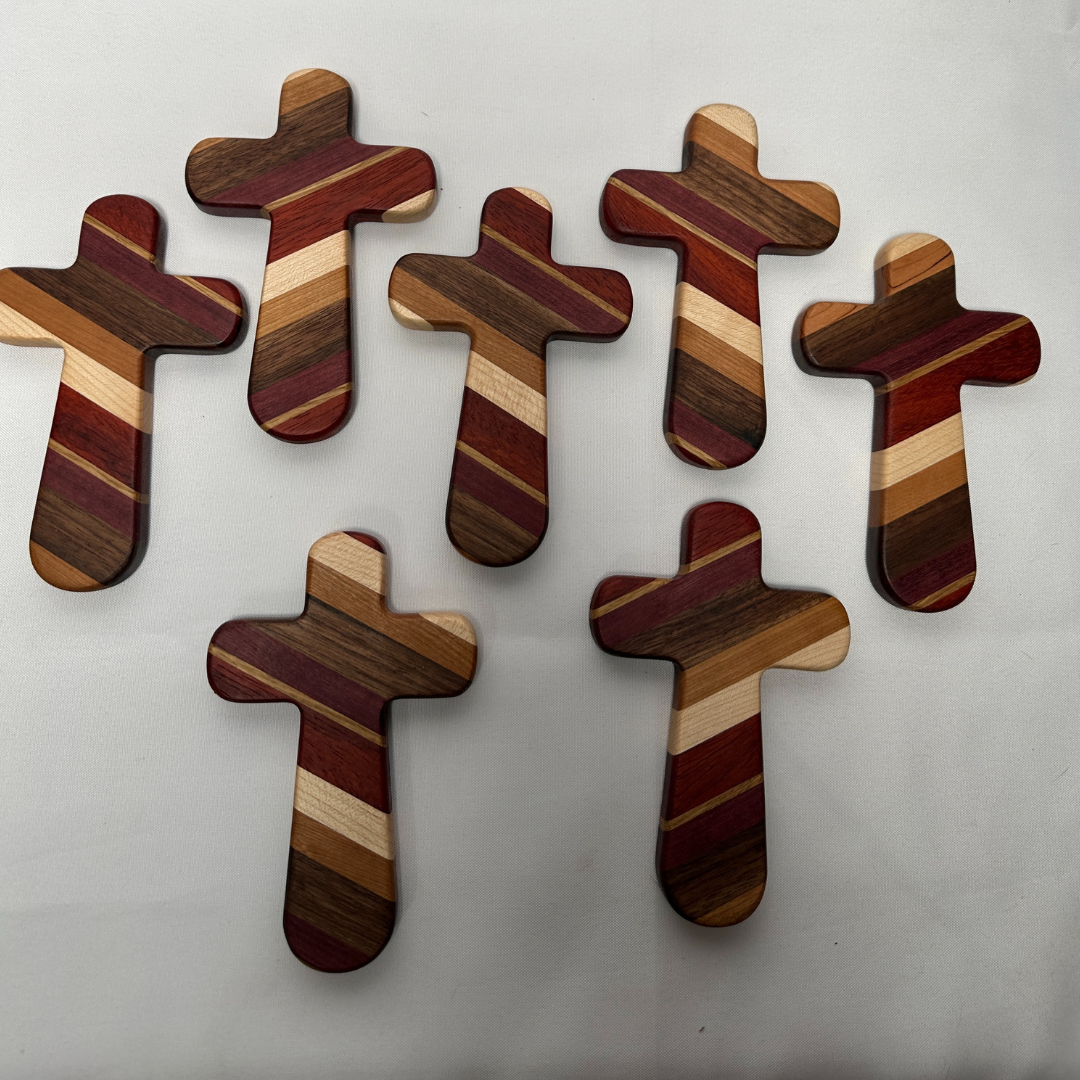 Add a timeless touch of faith and artistry to your home with this handcrafted wooden cross. Measuring 6-1/2" long by 4-1/8" wide, this cross is carefully crafted from premium strips of purple heart, paduak, white oak, hard maple, walnut, and cherry woods. Each cross is a unique piece, showcasing the natural beauty and rich tones of these high-quality hardwoods.