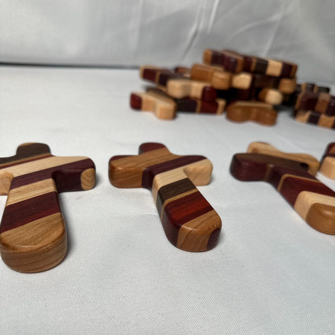 Experience the perfect blend of faith, craftsmanship, and personalization with our Handcrafted Wooden Prayer Cross. Measuring approximately 5" x 3-1/4", this hand-sized cross is thoughtfully designed for prayer, meditation, and comfort. Crafted from premium hardwoods, including purple heart, paduak, hard maple, walnut, white oak, and cherry, each cross showcases a stunning array of natural tones and textures.